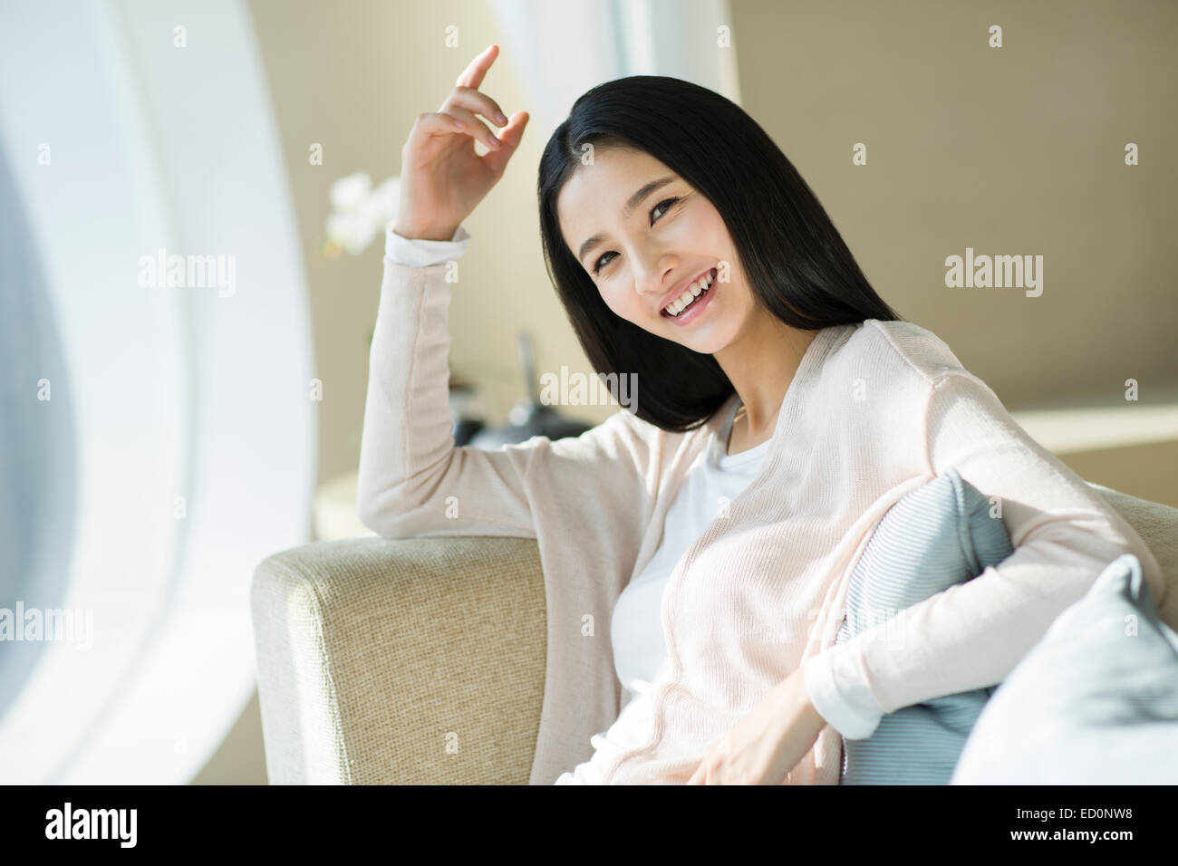Happy young woman sitting on sofa Stock Photo - Alamy