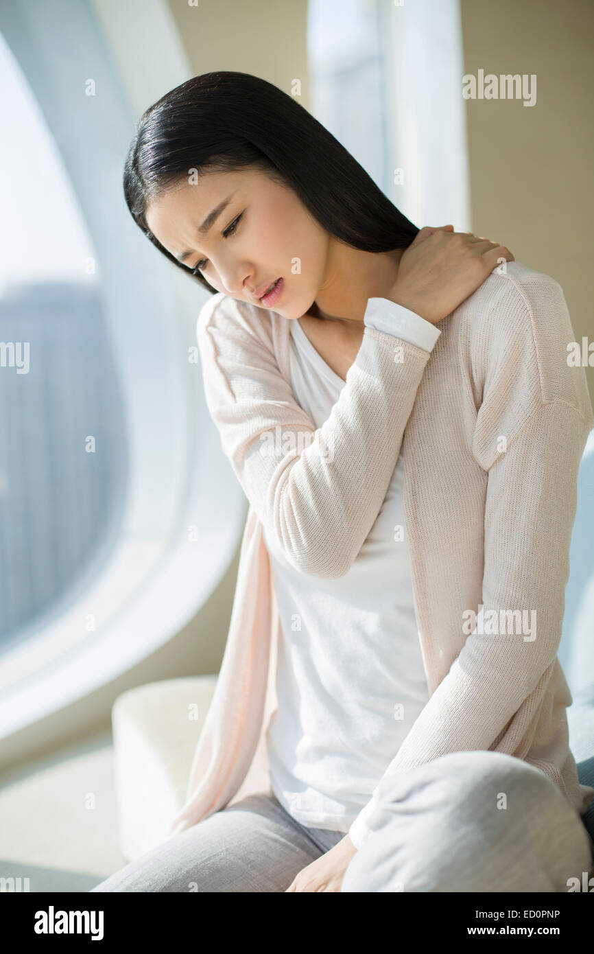 Young woman rubbing aching shoulders Stock Photo - Alamy