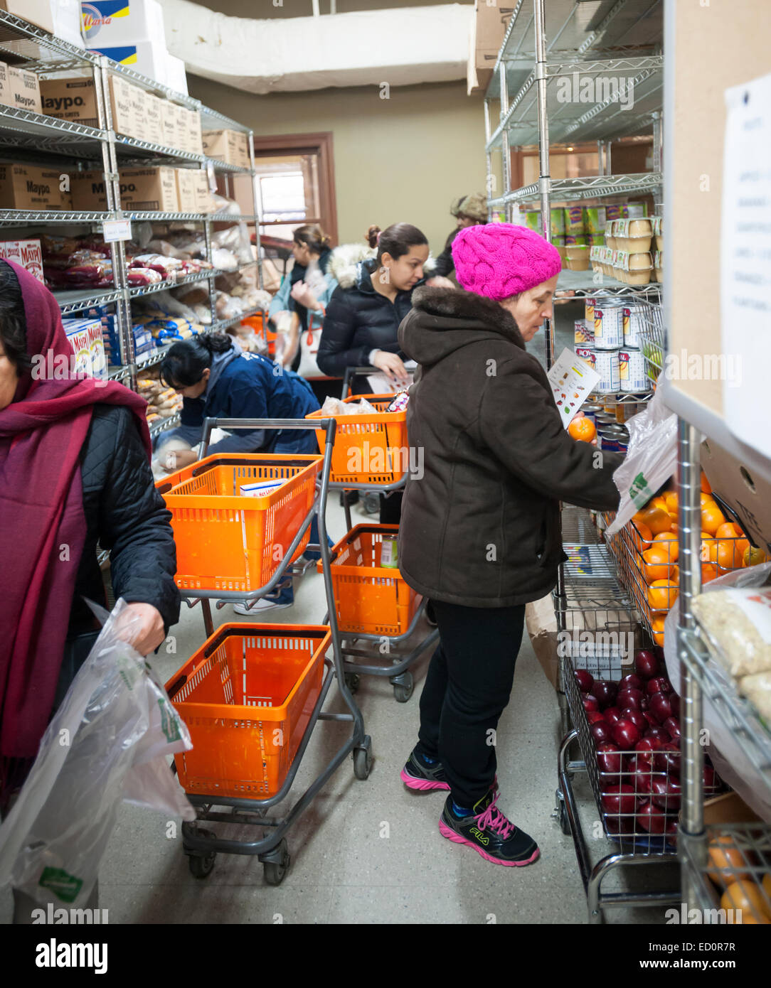 Clients at the West Side Campaign Against Hunger (WSCAH) receive groceries through the supermarket style food pantry on the Upper West Side neighborhood of New York on Friday, December 19, 2014. The clients get to choose their groceries for themselves and their families. In 2014 WSCAH provided food for over 1.1 million meals for nearly 10,000 families. The supermarket-style distribution promotes self-reliance and empowers the clients. (© Richard B. Levine) Stock Photo
