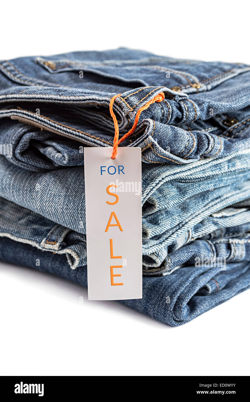 Pile of blue jeans with label isolated on white background. Selective focus on tag label. Stock Photo