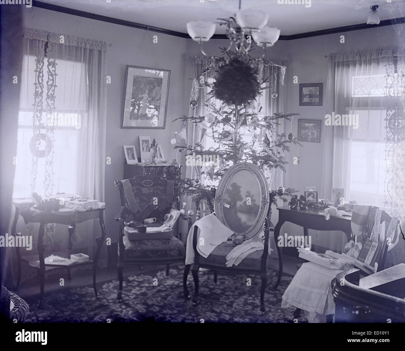 Antique, circa 1906 image, Christmas tree with opened presents on display, Boston, Massachusetts, USA. The book 'Jane Cable' by George Barr McCutcheon, the fifth best-selling novel in the United States in 1906, is visible on the chair. Stock Photo