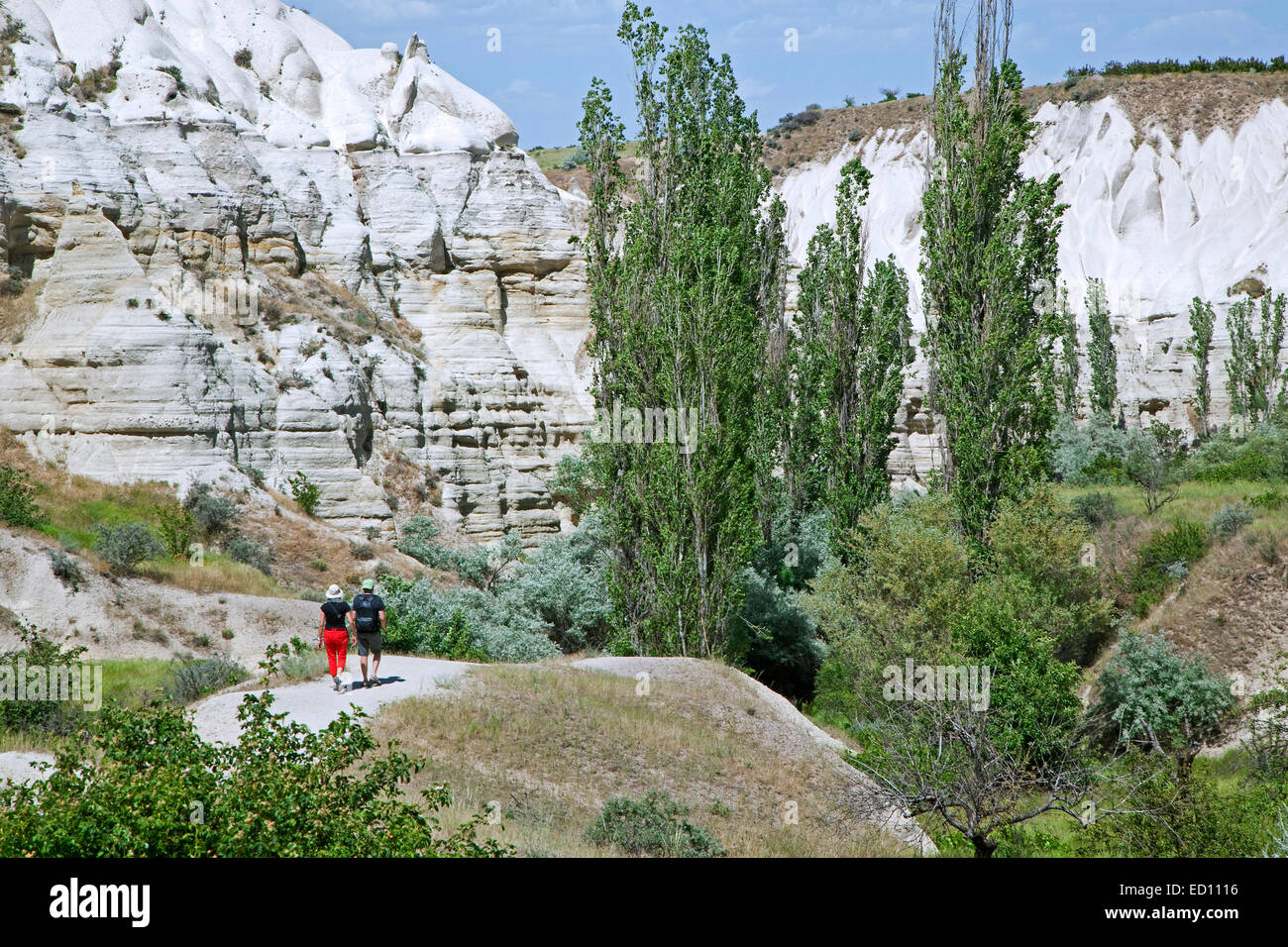 Tourists walking among eroded white sandstone rock formations at Cappadocia in Central Anatolia, Turkey Stock Photo