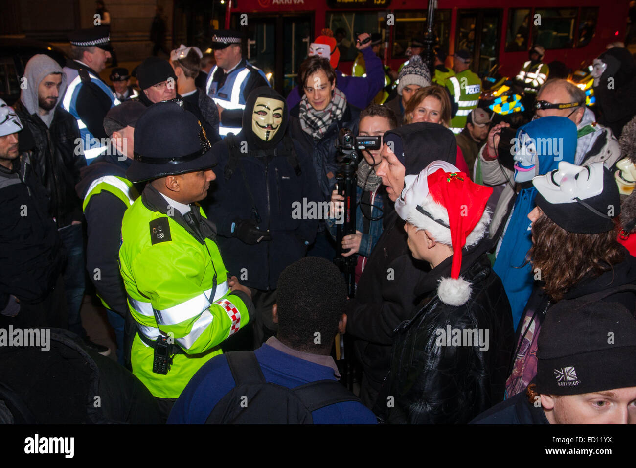 London, UK. 23rd Dec, 2014. Online activism group Anonymous march through London from the City to the BBC's HQ on Great Portland Street in protest against alleged biases and coverups of a 'paedophile ring'. PICTURED: Protesters discuss their position with a City of London police officer. Credit:  Paul Davey/Alamy Live News Stock Photo
