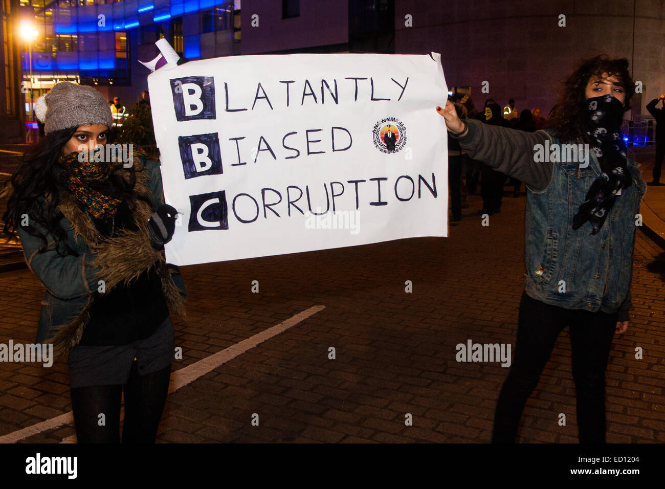 London, UK. 23rd Dec, 2014. Online activism group Anonymous march through London from the City to the BBC's HQ on Great Portland Street in protest against alleged biases and coverups of a 'paedophile ring'. PICTURED: Two young women parade a banner for the 'Blatantly Biased Corruption'. Credit:  Paul Davey/Alamy Live News Stock Photo