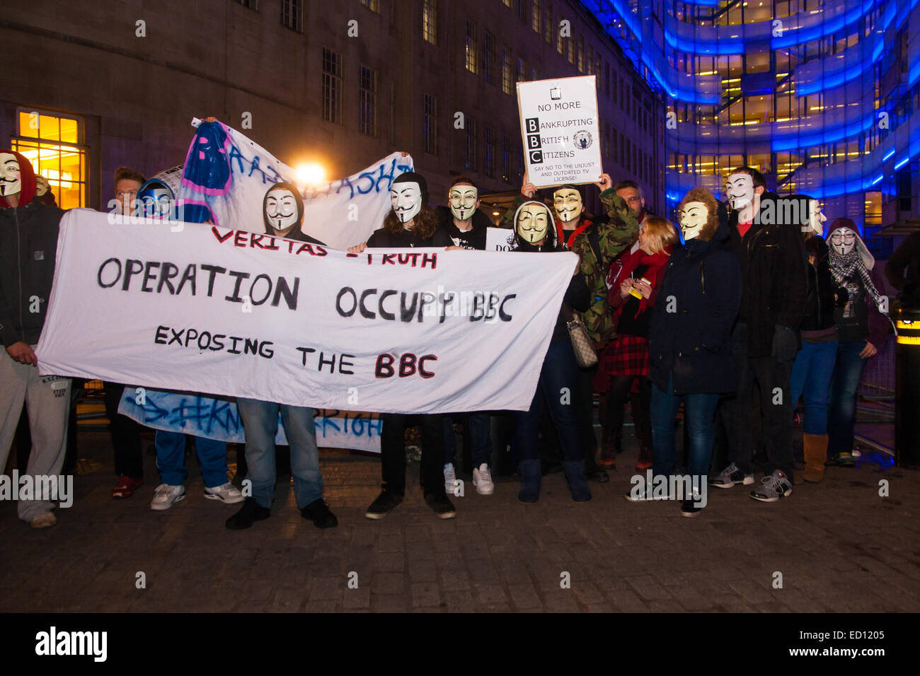 London, UK. 23rd Dec, 2014. Online activism group Anonymous march through London from the City to the BBC's HQ on Great Portland Street in protest against alleged biases and coverups of a 'paedophile ring'. PICTURED: The small group of protesters pose for a group shot outside the BBC Credit:  Paul Davey/Alamy Live News Stock Photo