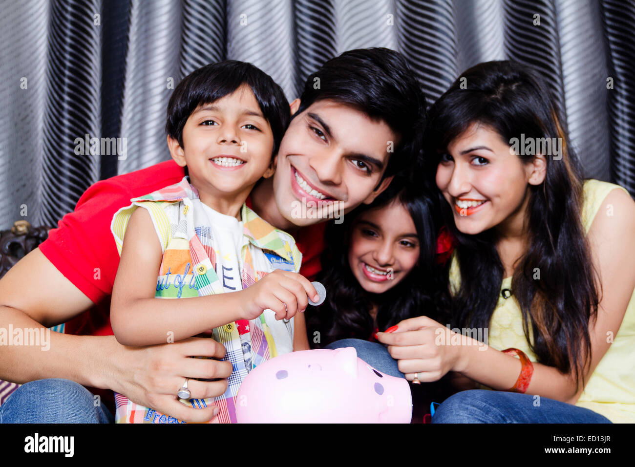 indian Parents with children Piggy Bank saving money Stock Photo