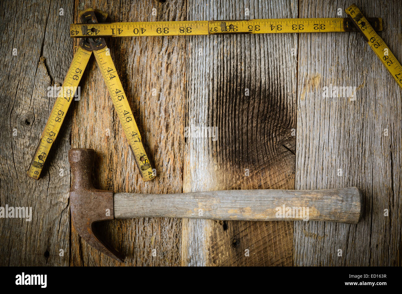 Old Tape Measure and Hammer for Construction on Rustic Wood Background