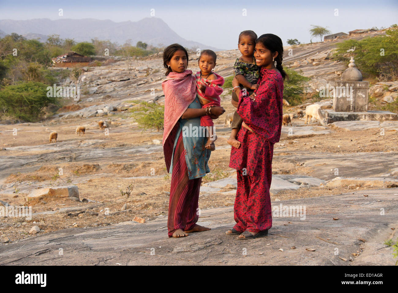 Garasia tribal girls tending babies on rocky hillside near Poshina, Gujarat, India Stock Photo