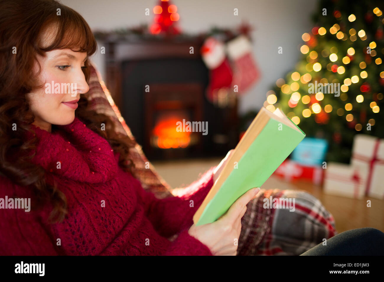 Beautiful redhead reading on the couch at christmas Stock Photo