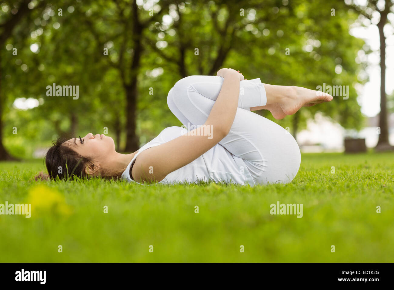 Side view of woman doing stretching exercises in park Stock Photo