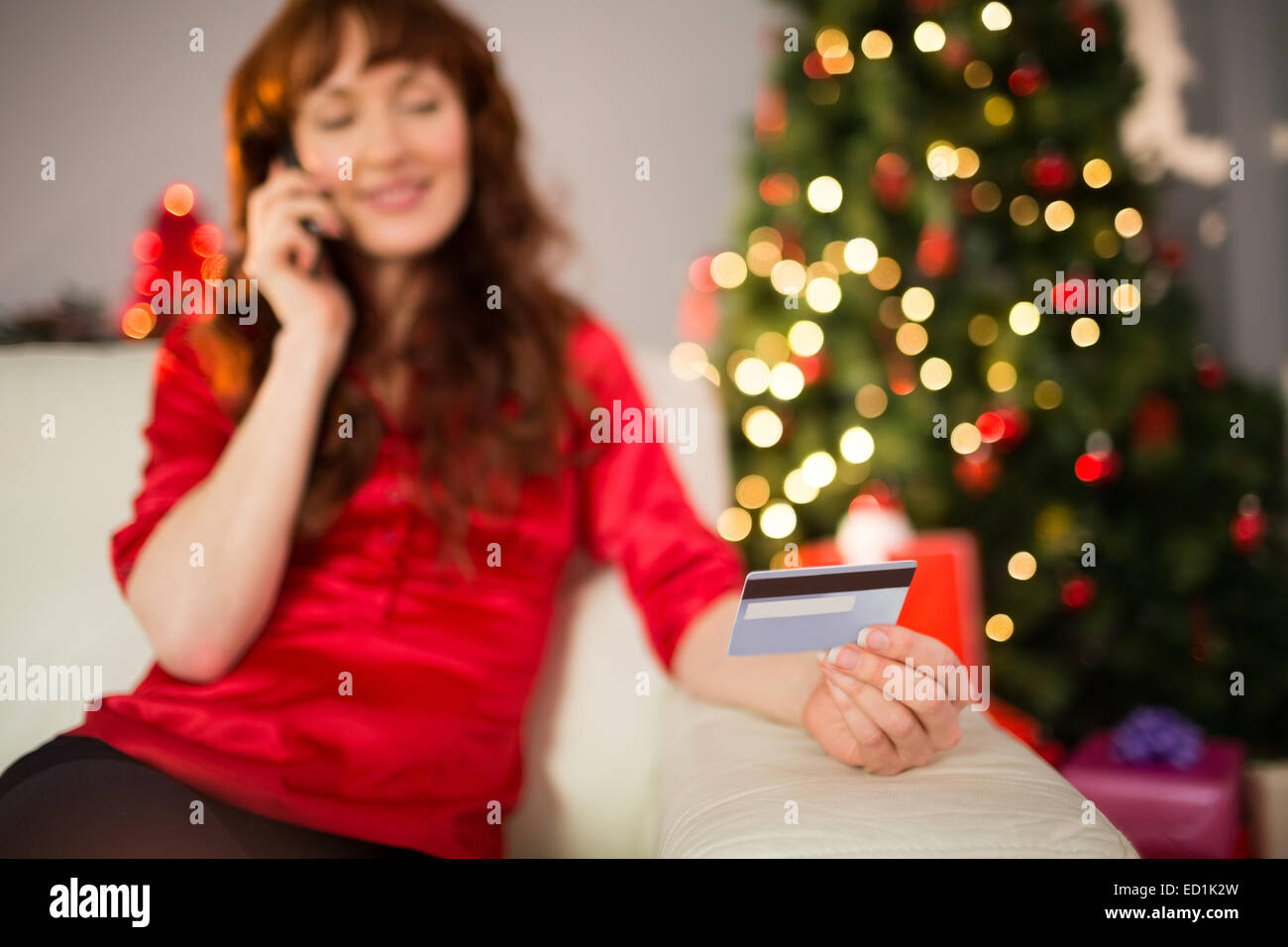 Smiling redhead phoning and holding credit card Stock Photo
