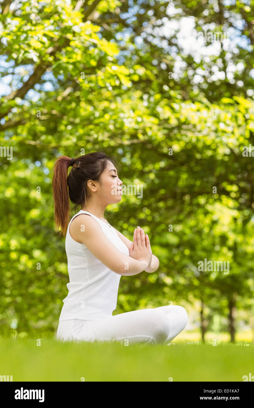 Healthy woman sitting with joined hands at park Stock Photo