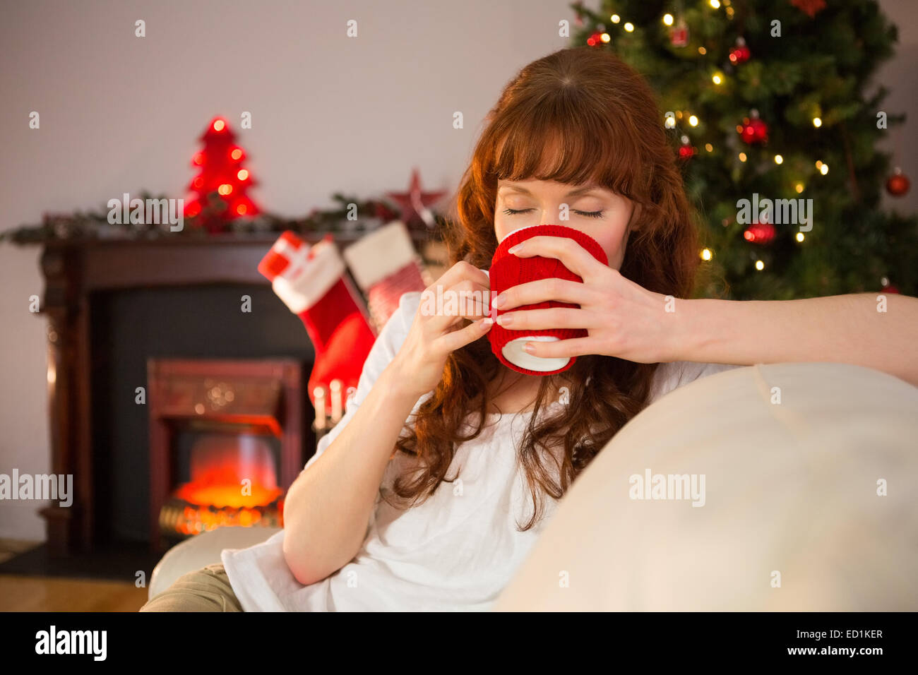 Pretty redhead sitting on couch drinking hot chocolate Stock Photo