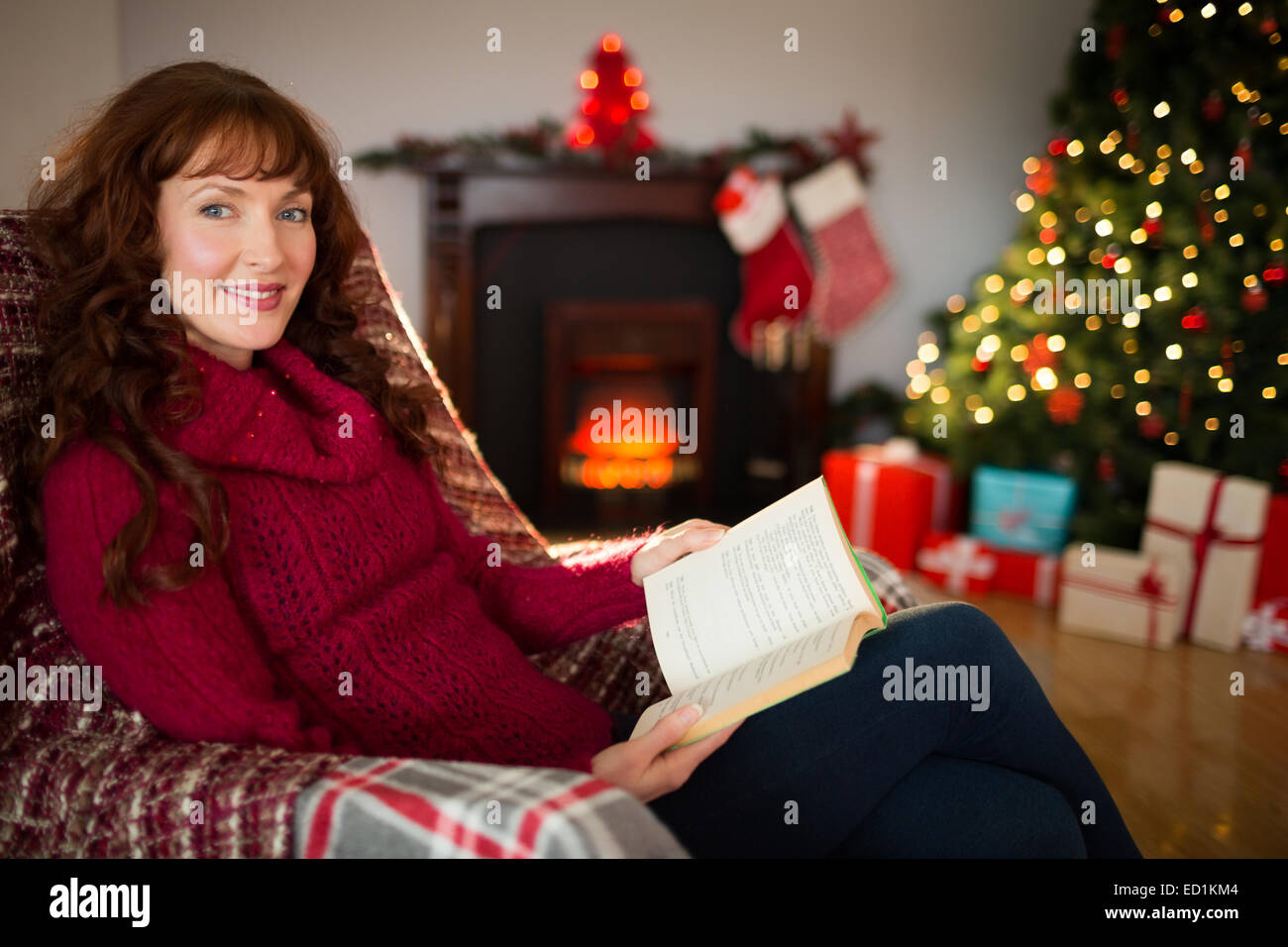 Cheerful redhead reading on the armchair at christmas Stock Photo