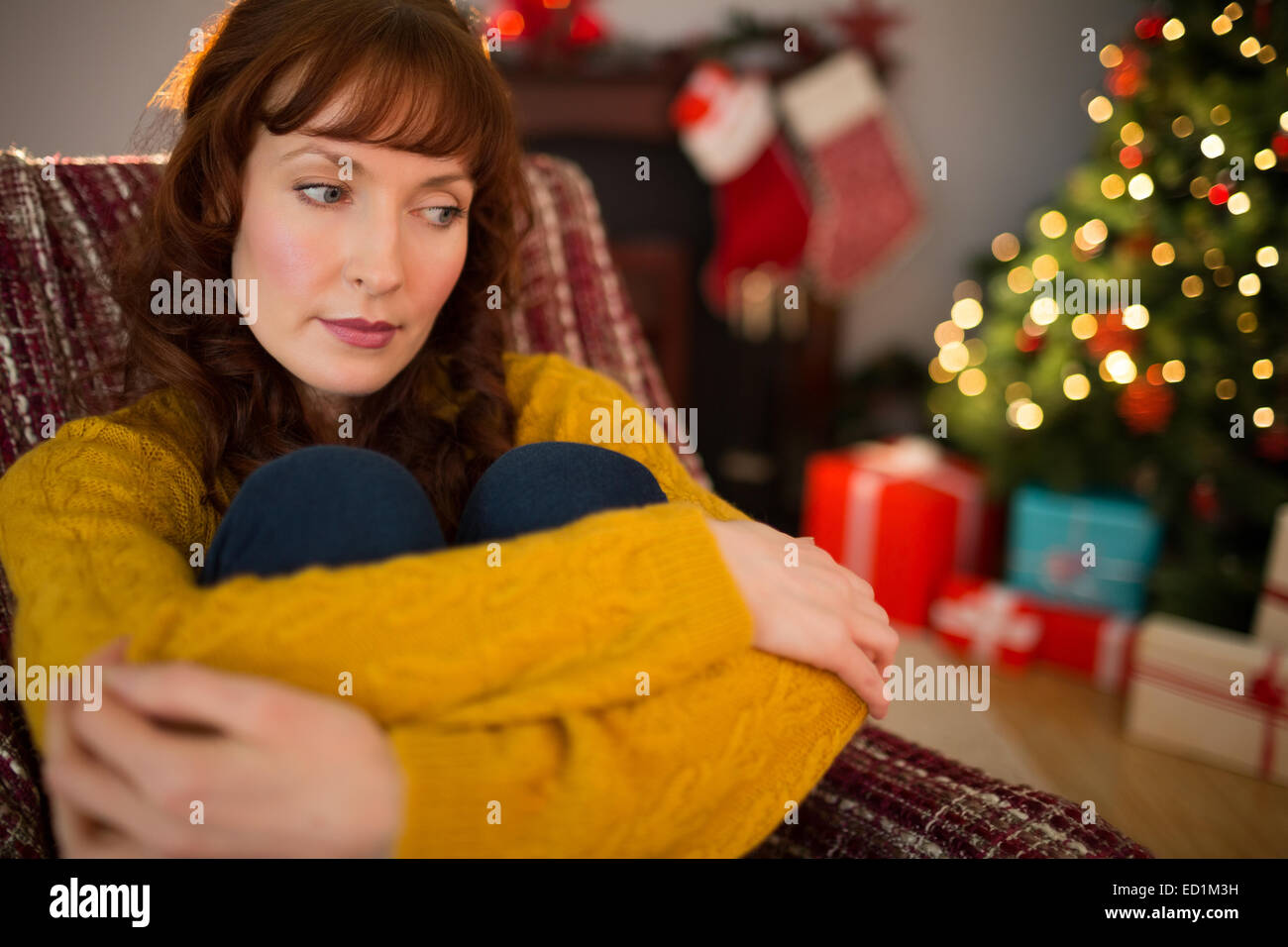 Thoughtful redhead sitting on the armchair at christmas Stock Photo