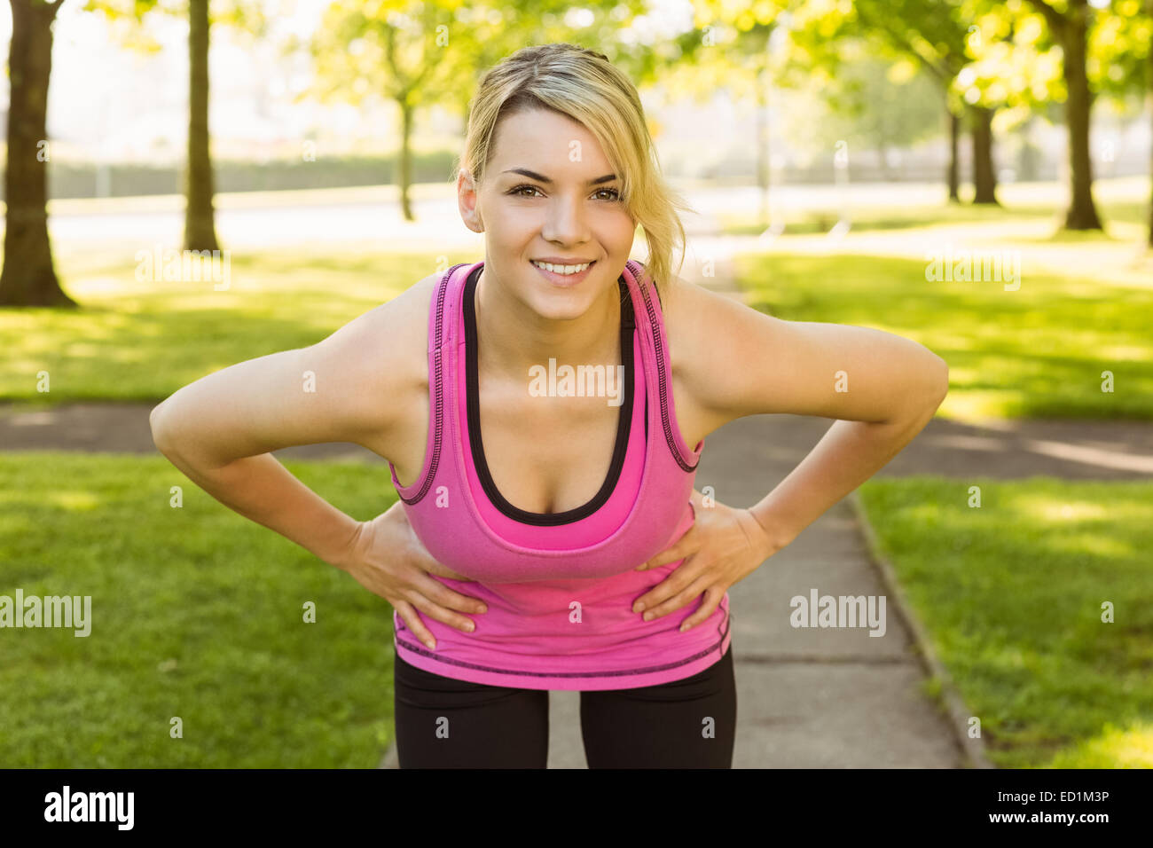 Fit blonde smiling at camera in the park Stock Photo - Alamy