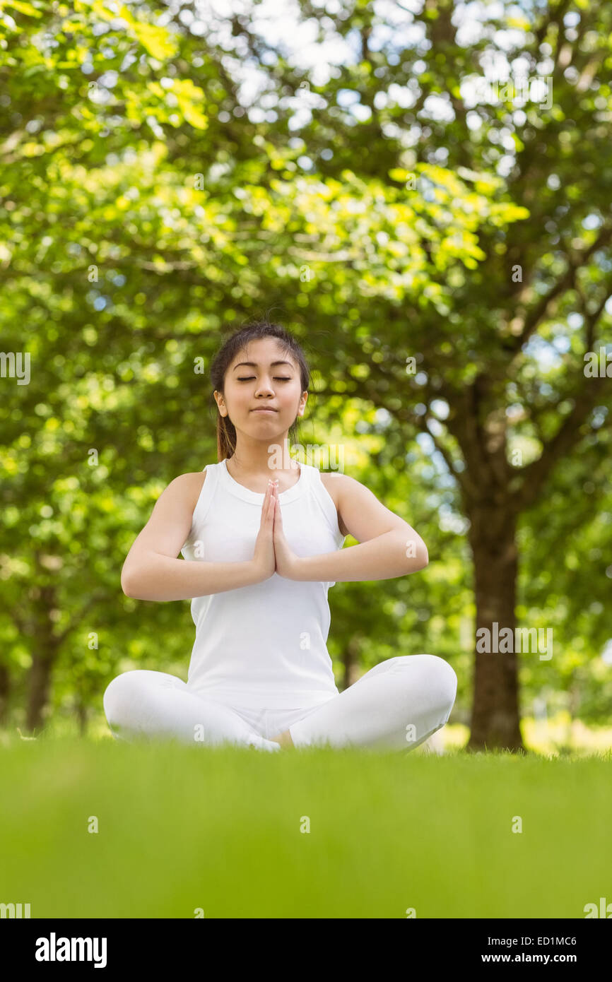 Healthy woman sitting with joined hands at park Stock Photo