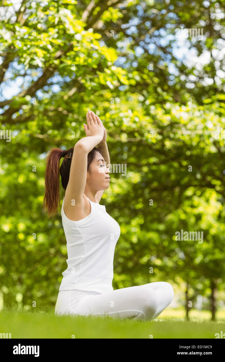 Healthy woman sitting with joined hands over head at park Stock Photo