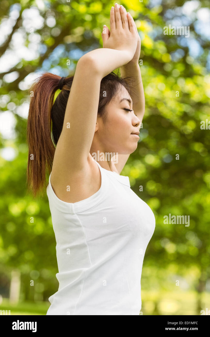 Healthy woman with joined hands over head at park Stock Photo