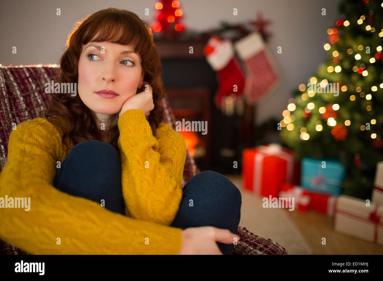 Pretty redhead thinking on the armchair at christmas Stock Photo