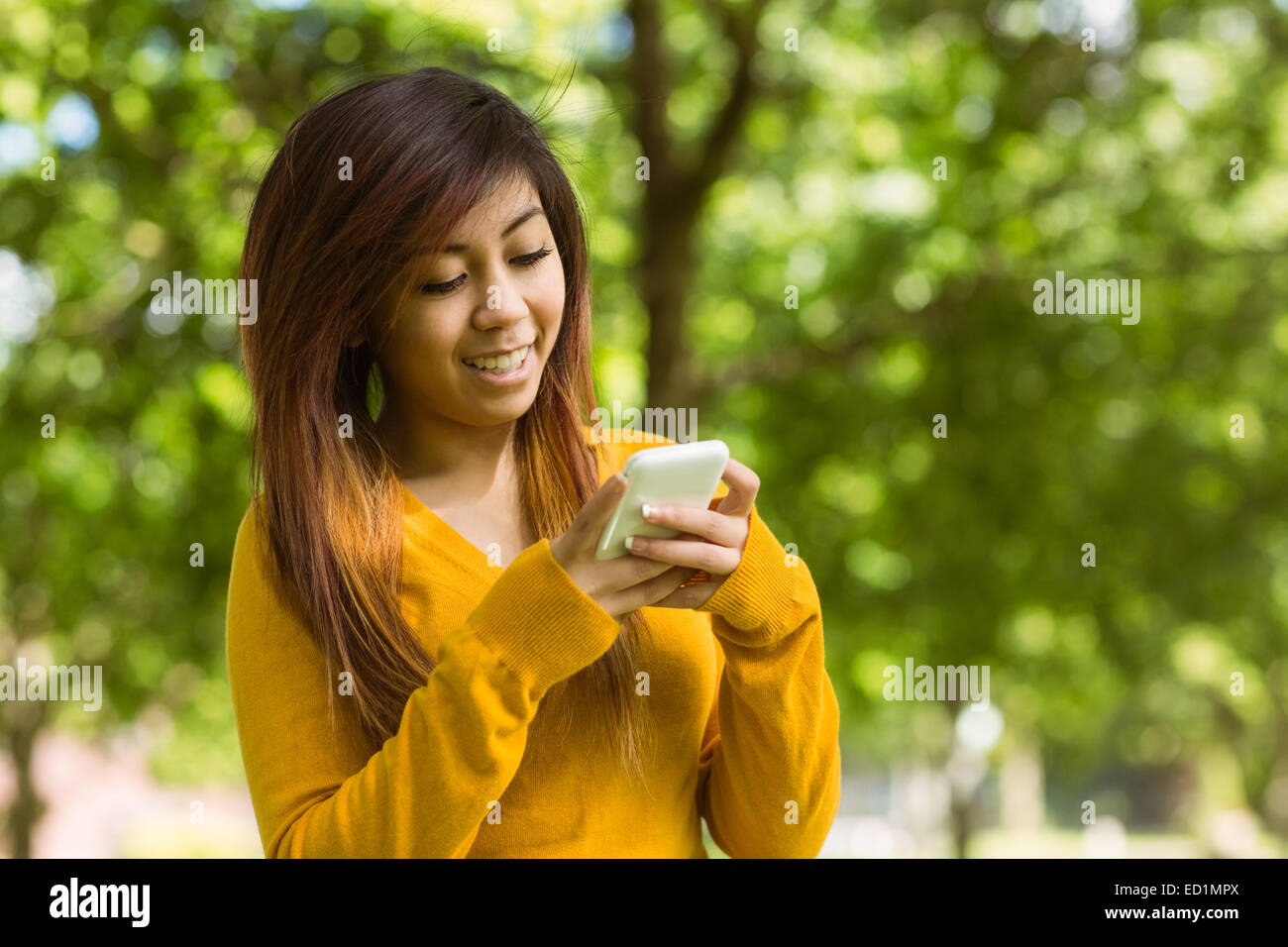 Woman text messaging in park Stock Photo