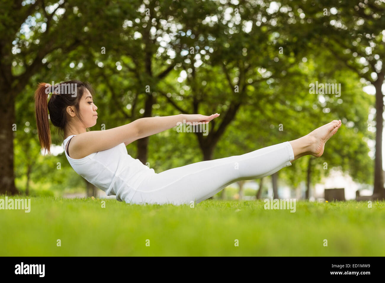Side view of doing the boat pose in park Stock Photo