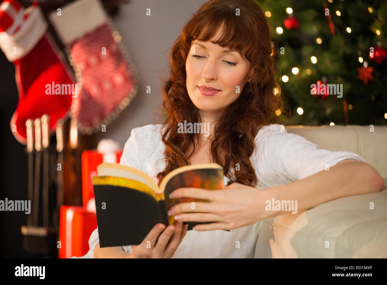 Interested redhead sitting on the floor reading Stock Photo