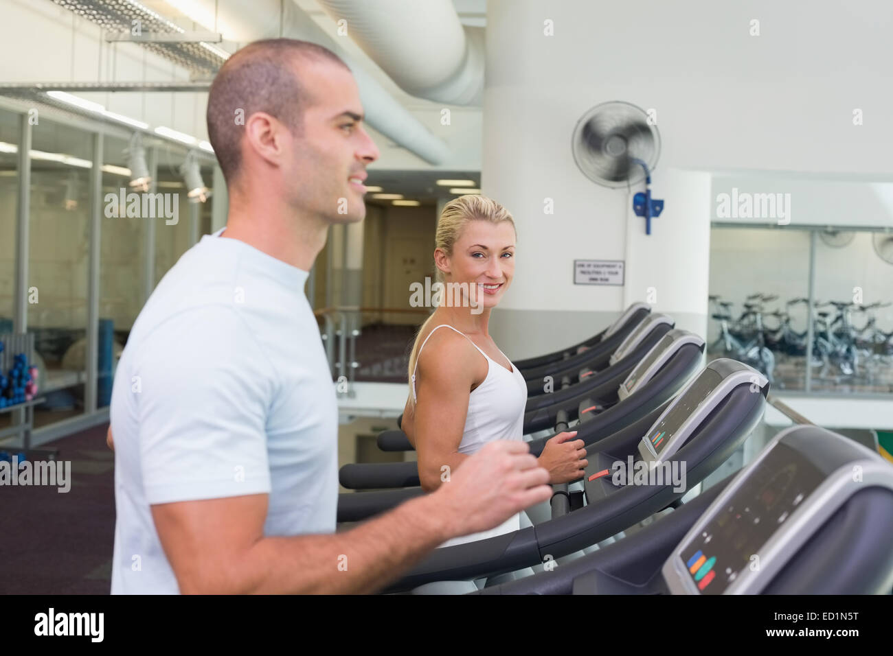 Side view of couple running on treadmills at gym Stock Photo - Alamy