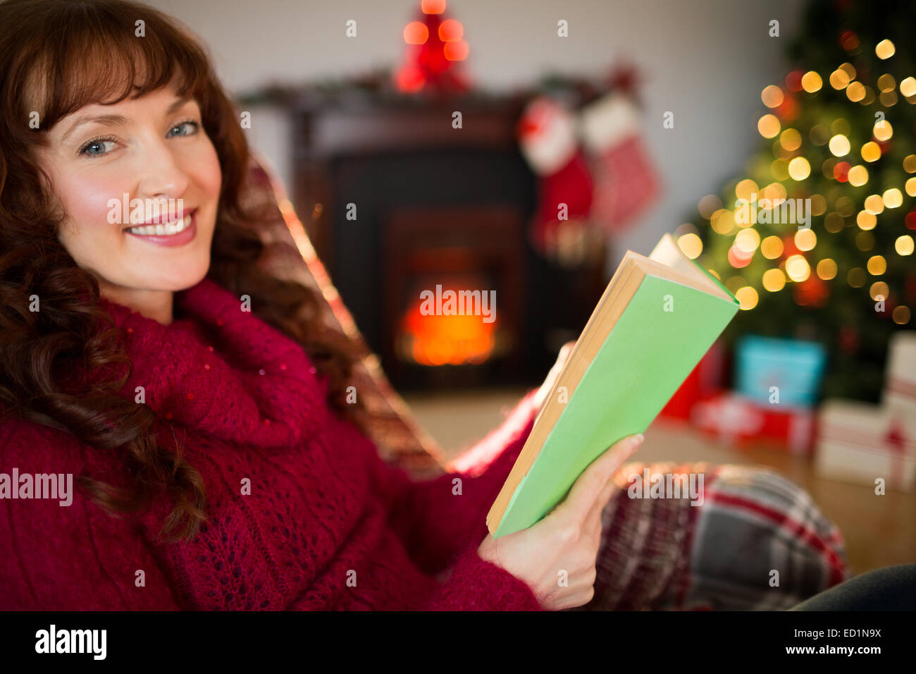 Smiling red hair reading on the couch at christmas Stock Photo