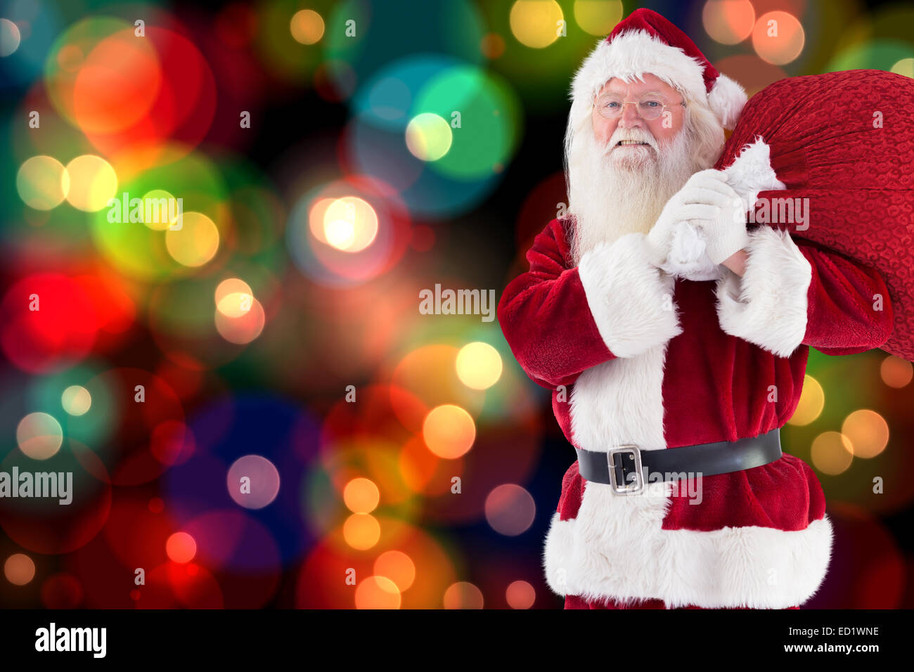 Composite image of santa carries his red bag and smiles Stock Photo - Alamy