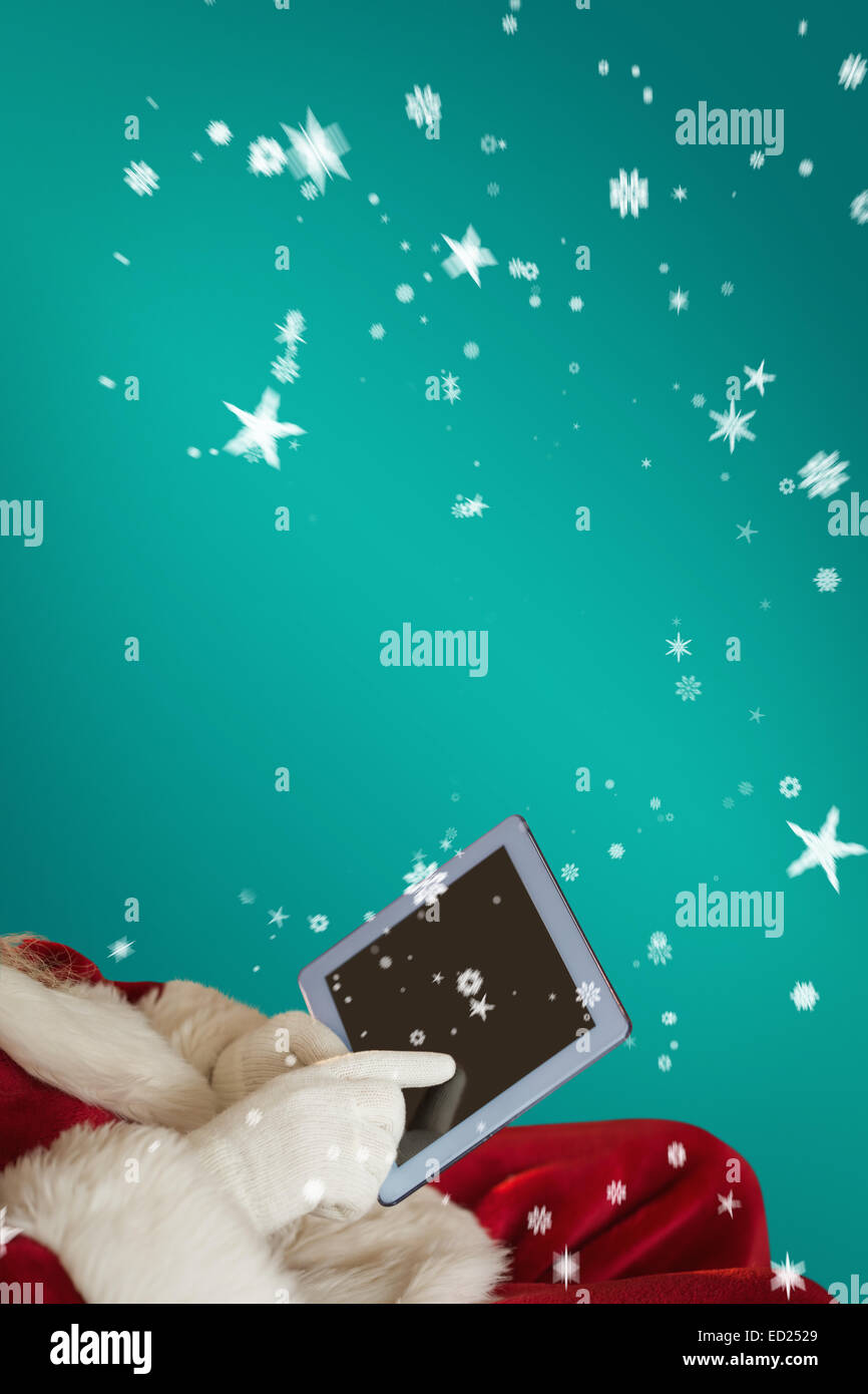 Composite image of santa using tablet on the armchair Stock Photo - Alamy