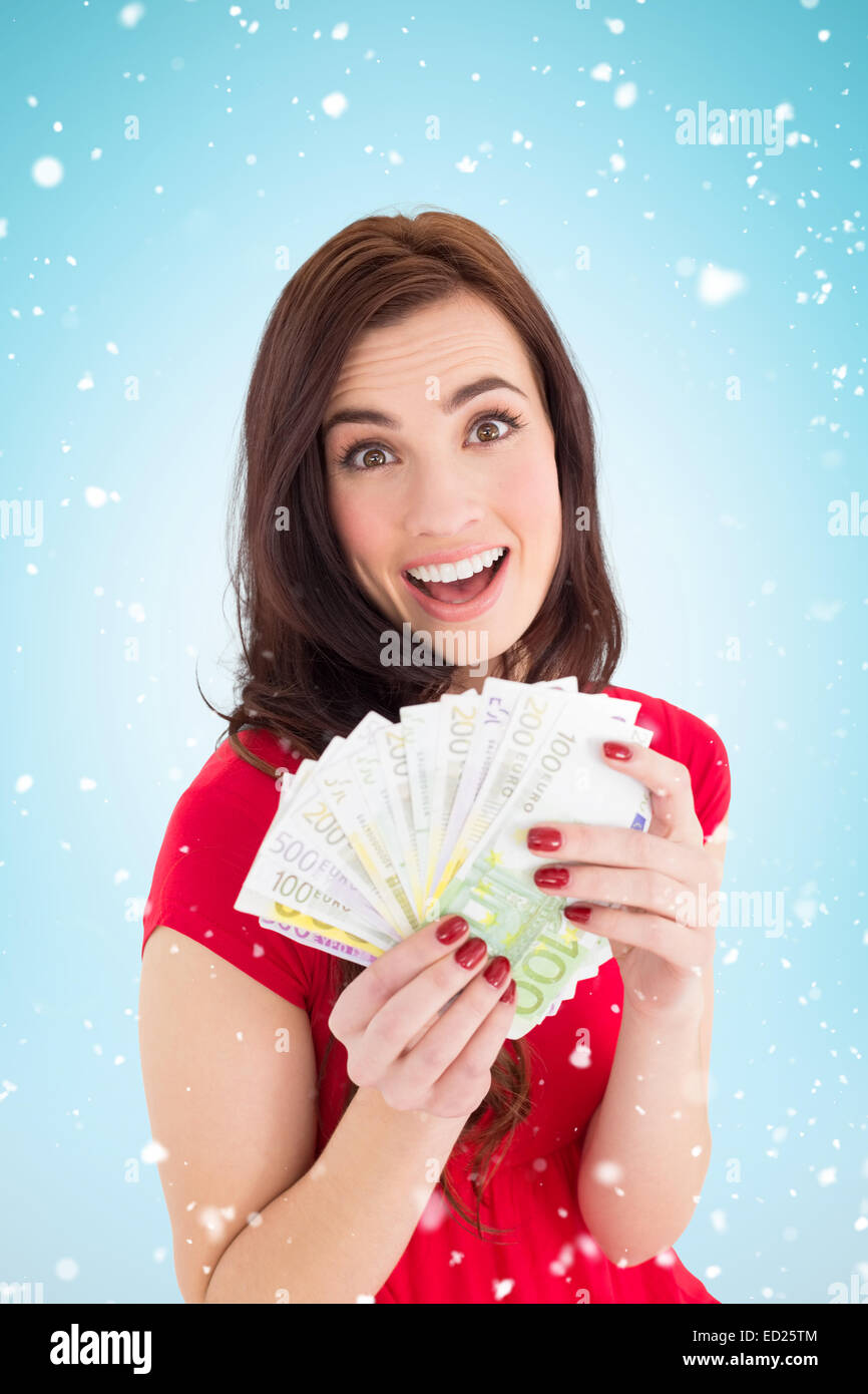Composite image of excited brunette holding her cash Stock Photo - Alamy