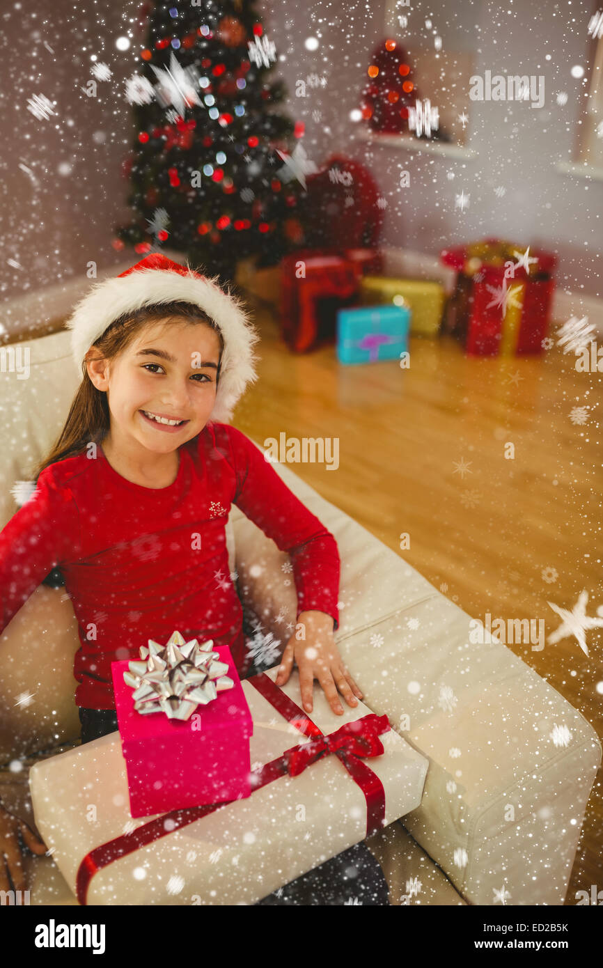 Composite image of festive little girl smiling at camera with gifts ...