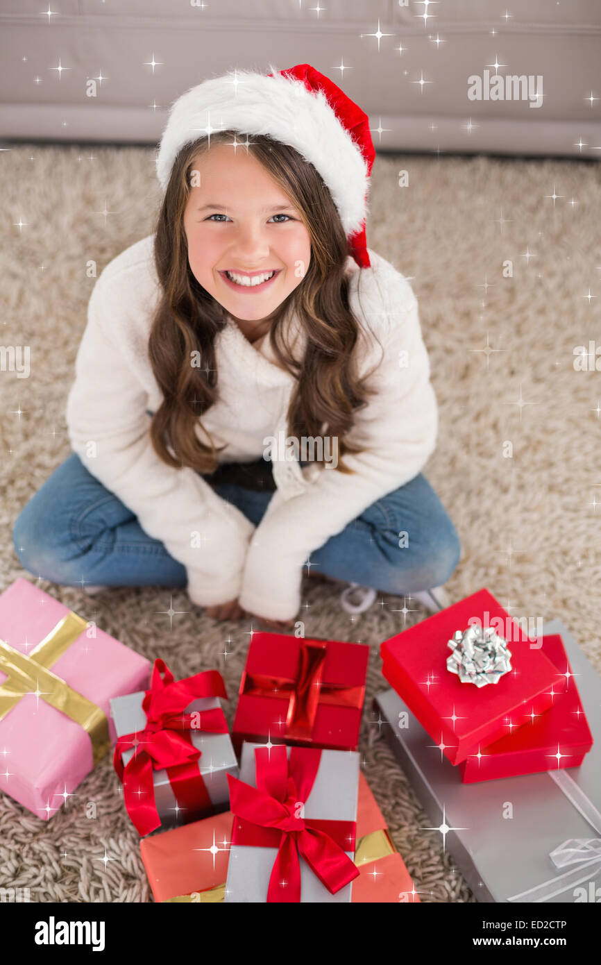 Composite image of festive little girl smiling at camera with gifts ...