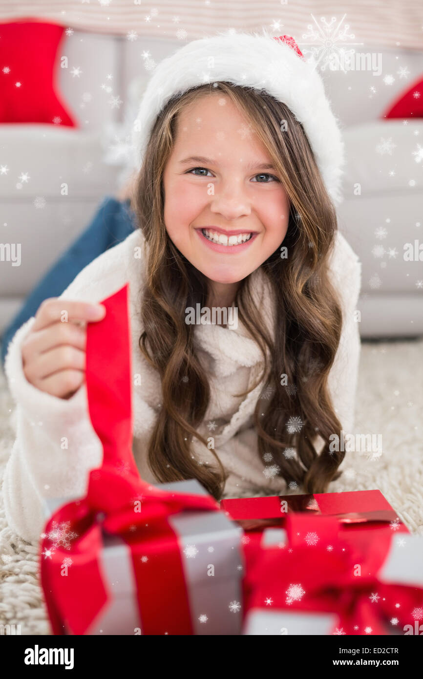 Composite image of festive little girl smiling at camera with gifts ...
