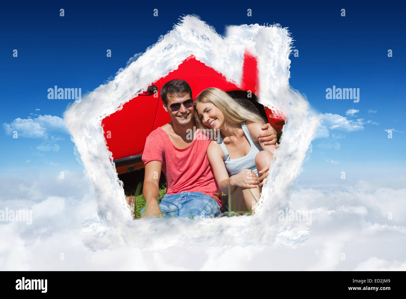 Composite image of smiling couple sitting on the grass having picnic together Stock Photo