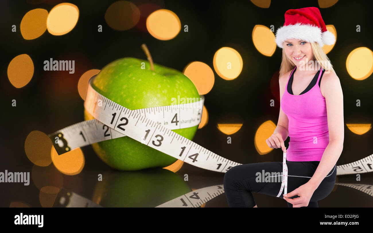 Composite image of fit festive young blonde measuring her thigh Stock Photo