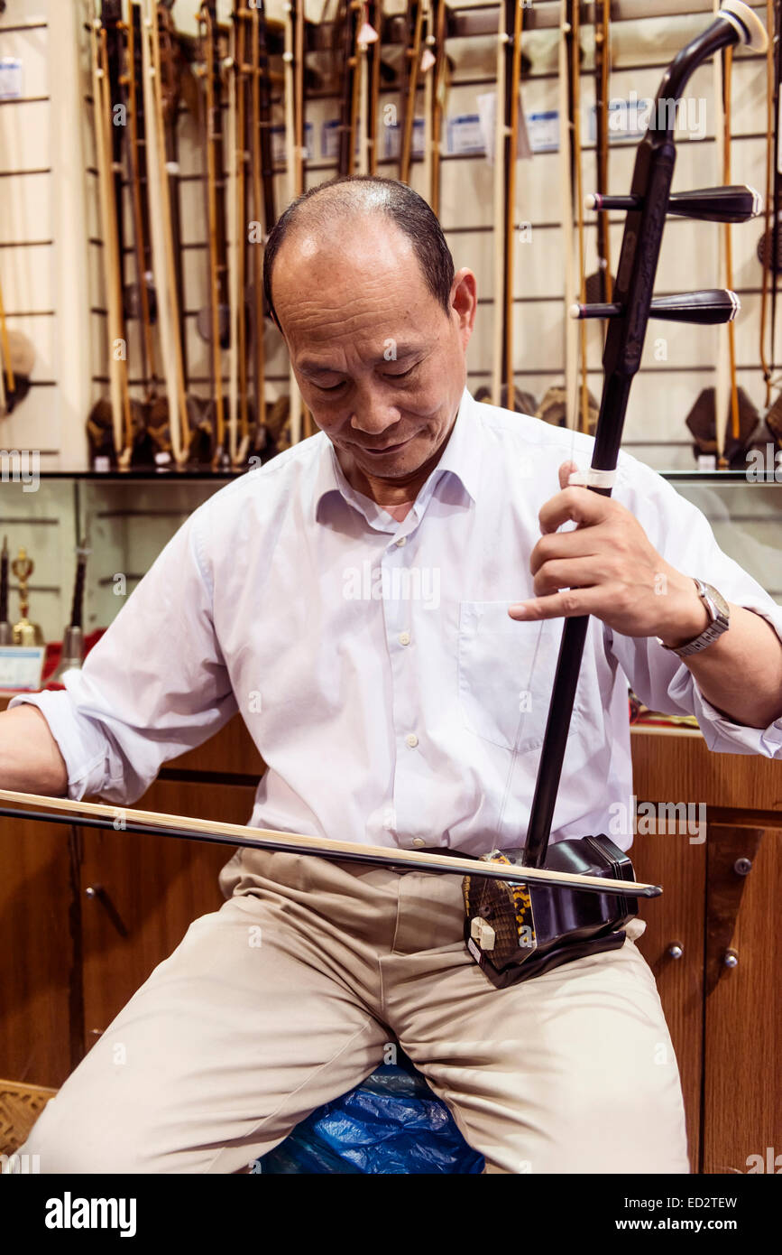 Music store owner in Shanghai, China plays Erhu Chinese fiddle Stock Photo