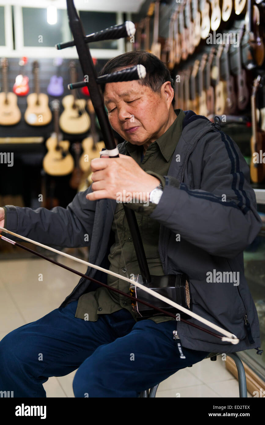 Music instrument store owner in Shanghai, China plays Erhu Chinese fiddle Stock Photo