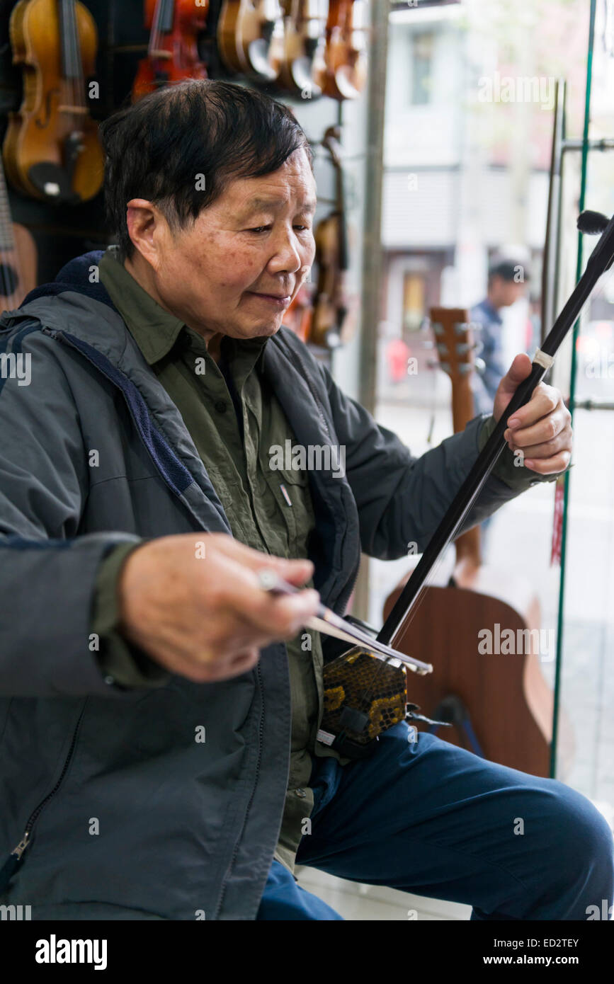 Music instrument store owne plays Erhu Chinese fiddler in Shanghai, China Stock Photo