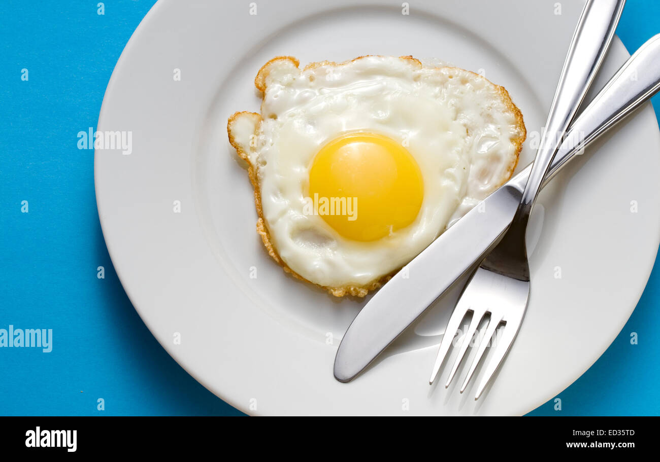 Fried egg on a plate with flatware Stock Photo