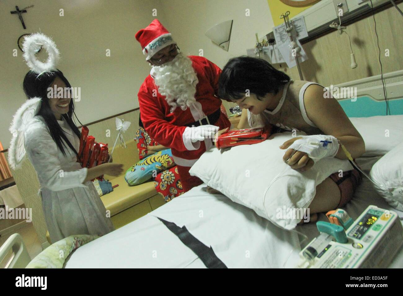 Semarang, Indonesia. 25th Dec, 2014. A man dressed as Santa Claus gives a patient presents for Christmas at St. Elisabeth hospital in Semarang, Indonesia, Dec. 25, 2014. Credit:  Dhana Kencana/Xinhua/Alamy Live News Stock Photo