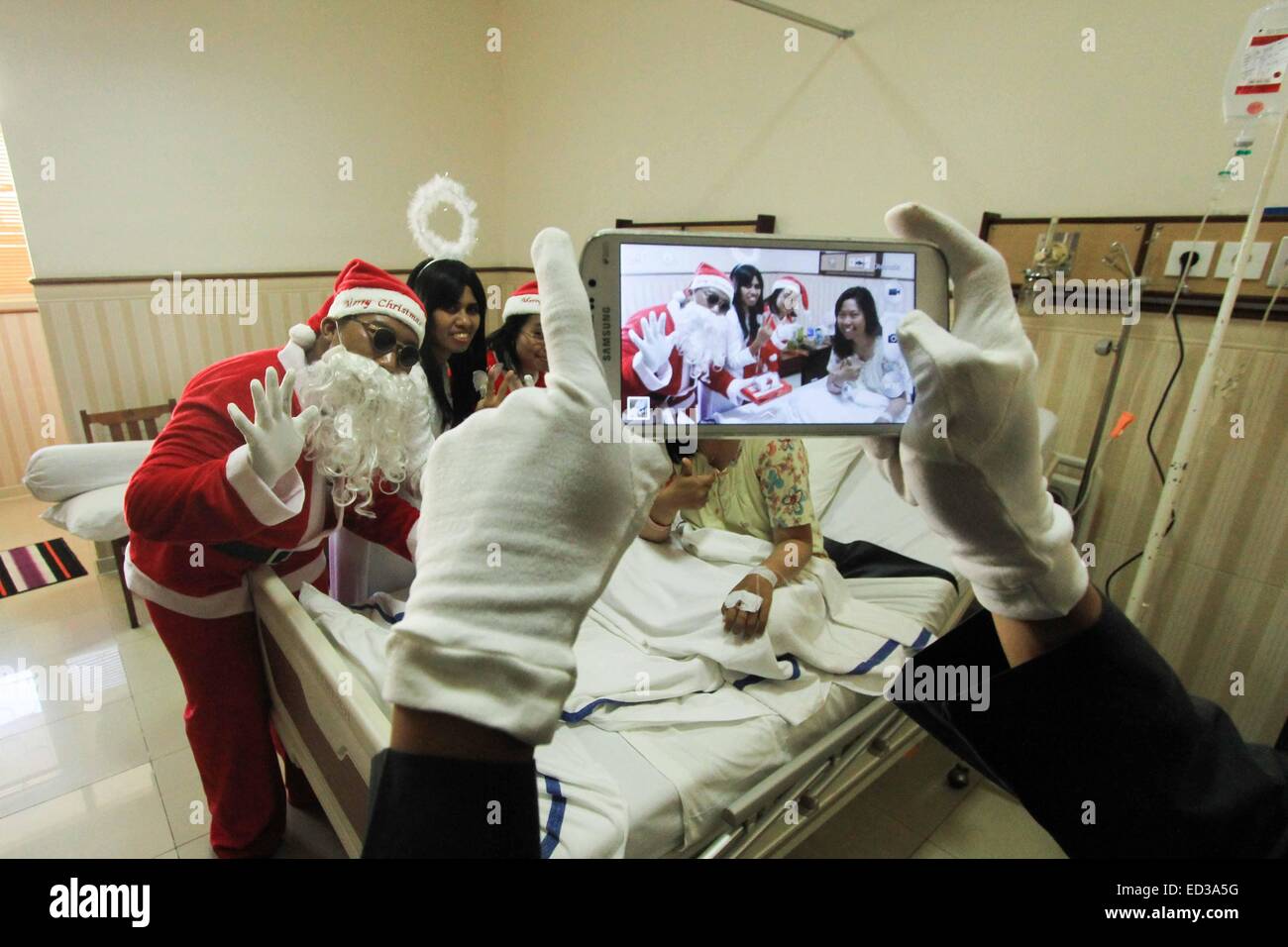 Semarang, Indonesia. 25th Dec, 2014. A man dressed as Santa Claus poses for photos with patients on Christmas at St. Elisabeth hospital in Semarang, Indonesia, Dec. 25, 2014. Credit:  Dhana Kencana/Xinhua/Alamy Live News Stock Photo