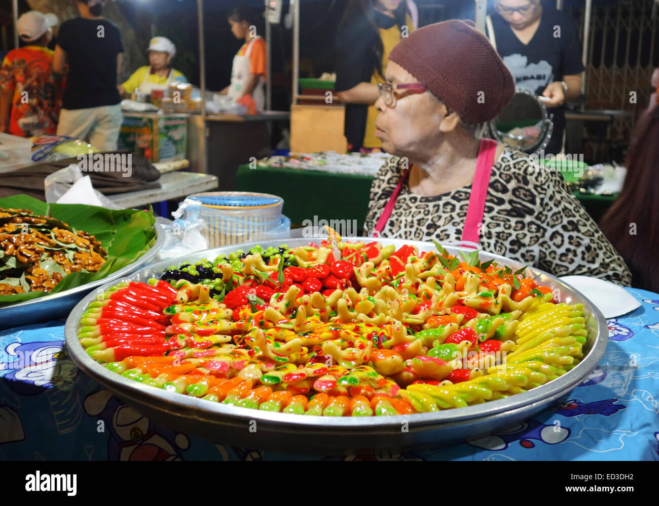 Older woman, Thai street food. vendor at night market, offering Kao Noom Look Choup, thai desert, Krabi, Thailand, Asia. Stock Photo