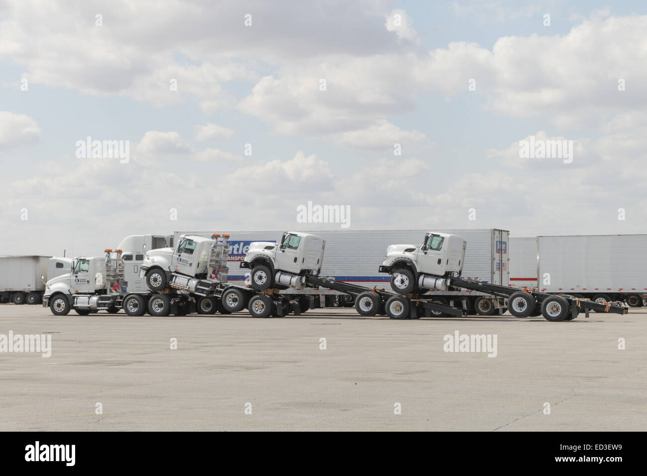 Semi truck in parking lot hauling 3 more tractors piggy back style