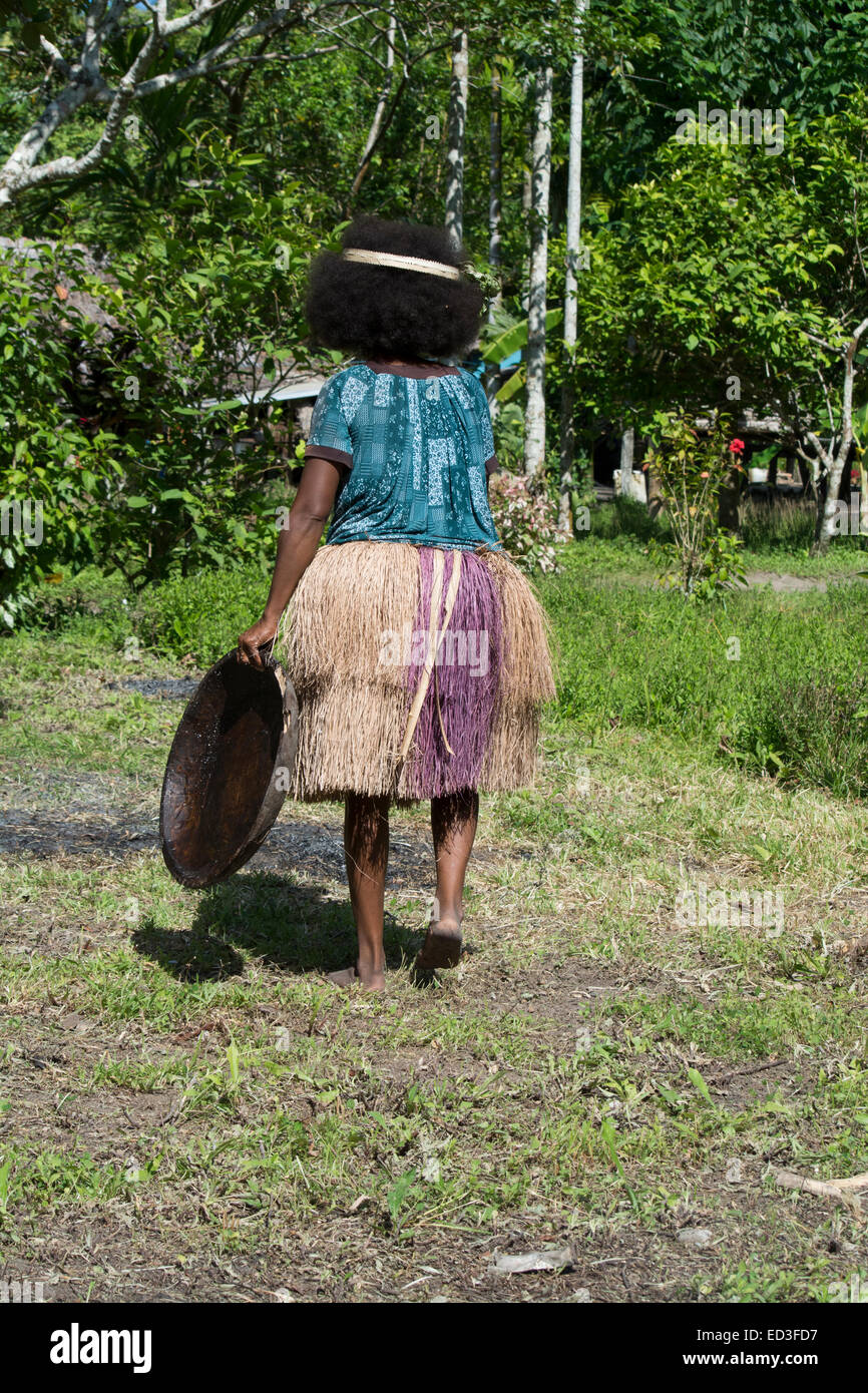 Melanesia, Papua New Guinea, Dobu Island. Woman in grass skirt with wooden plate. Stock Photo
