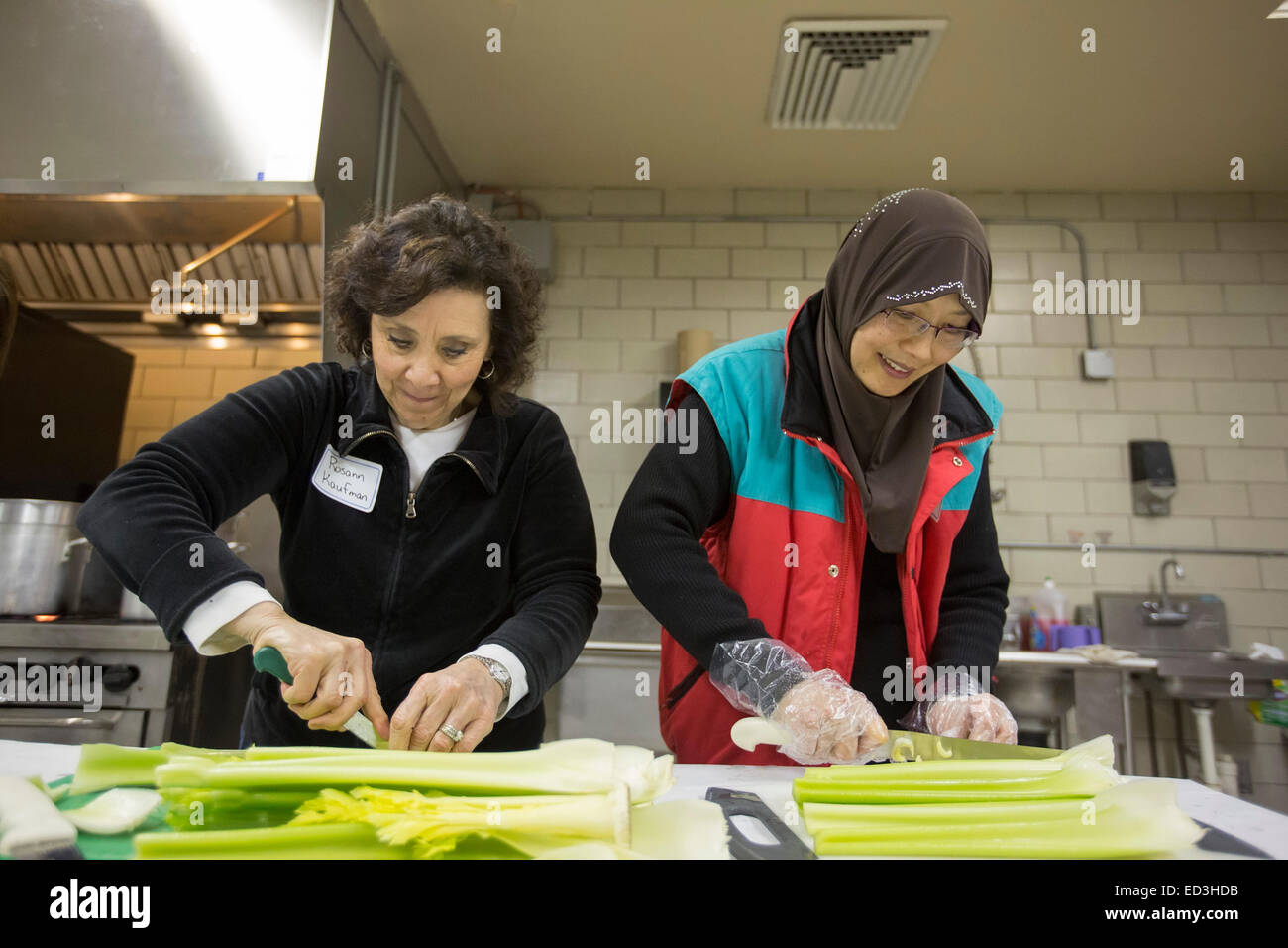 Oak Park, Michigan USA - 25 December 2014 - Jewish and Muslim volunteers prepare Christmas Day meals for the homeless at Congregation Beth Shalom as part of 'Mitzvah Day.' Mitzvah Day has become a Christmas tradition in the Detroit area as Jews, joined more recently by Muslims, volunteer at social service agencies. Rosann Kaufman (left) and Zenobia Lee chopped celery for tuna salad. Credit:  Jim West/Alamy Live News Stock Photo