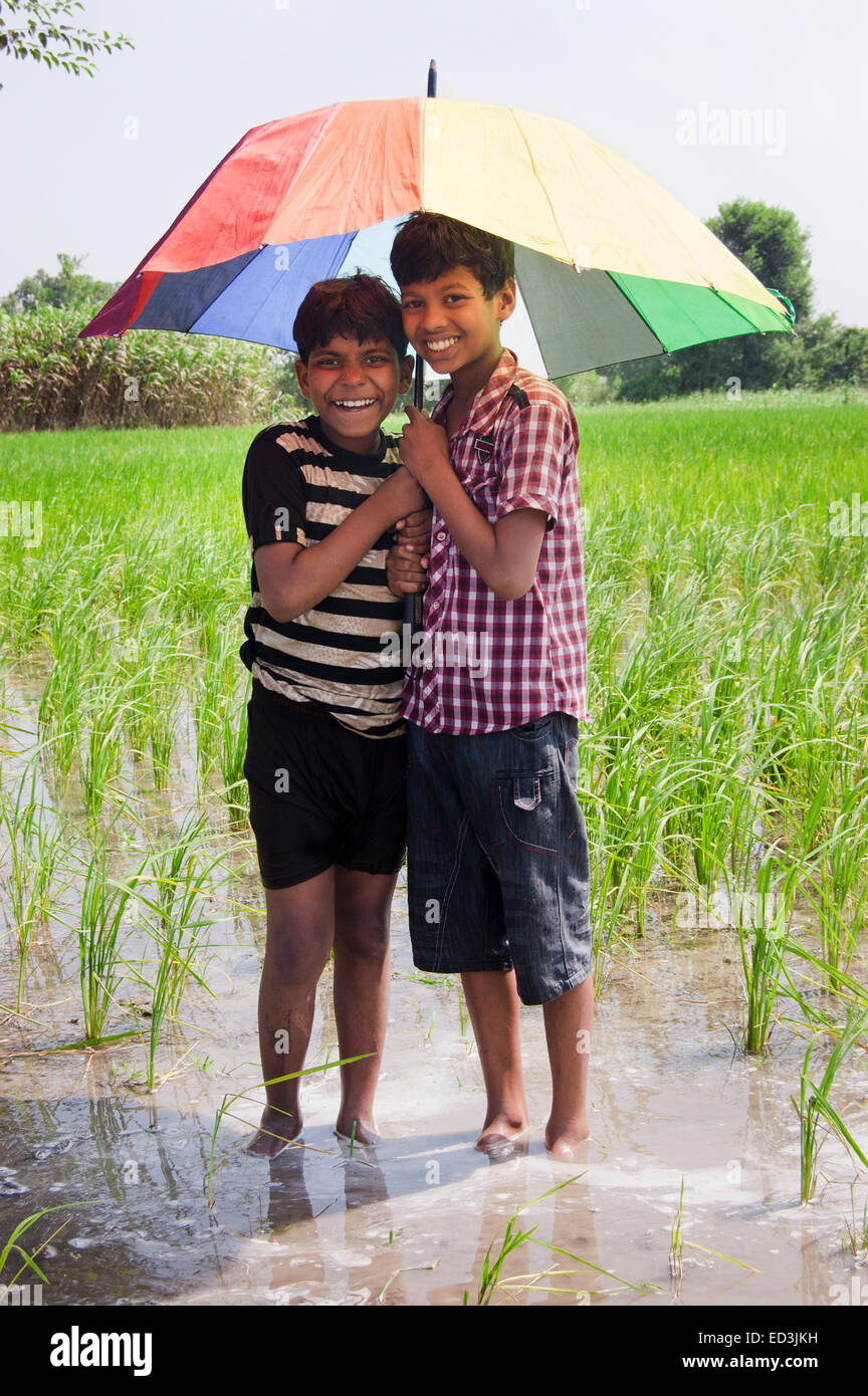 2 indian rural children boys holding Umbrella rain season enjoy Stock