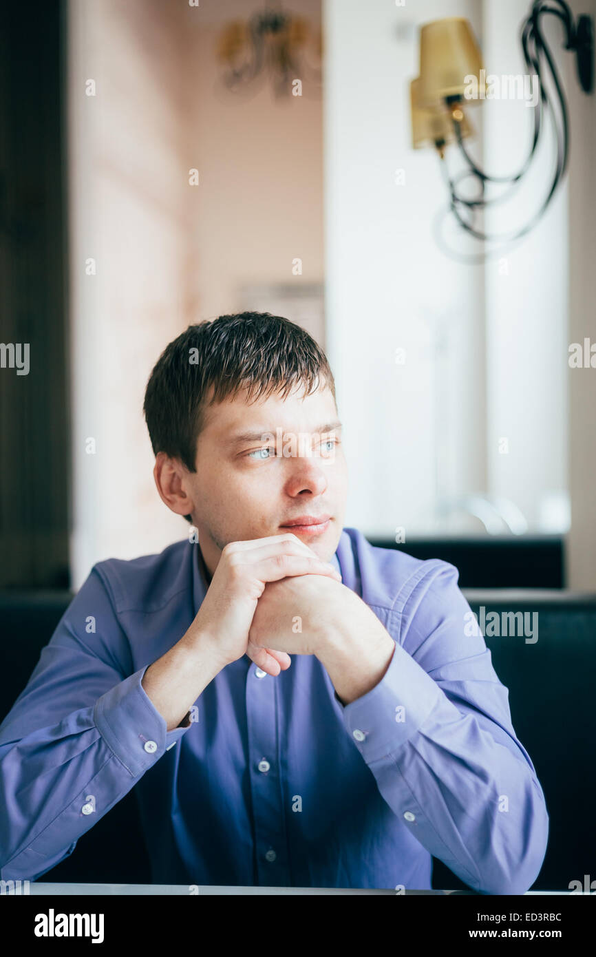 Caucasian Handsome Thinking Man In Blue Shirt Sitting In Cafe Stock Photo