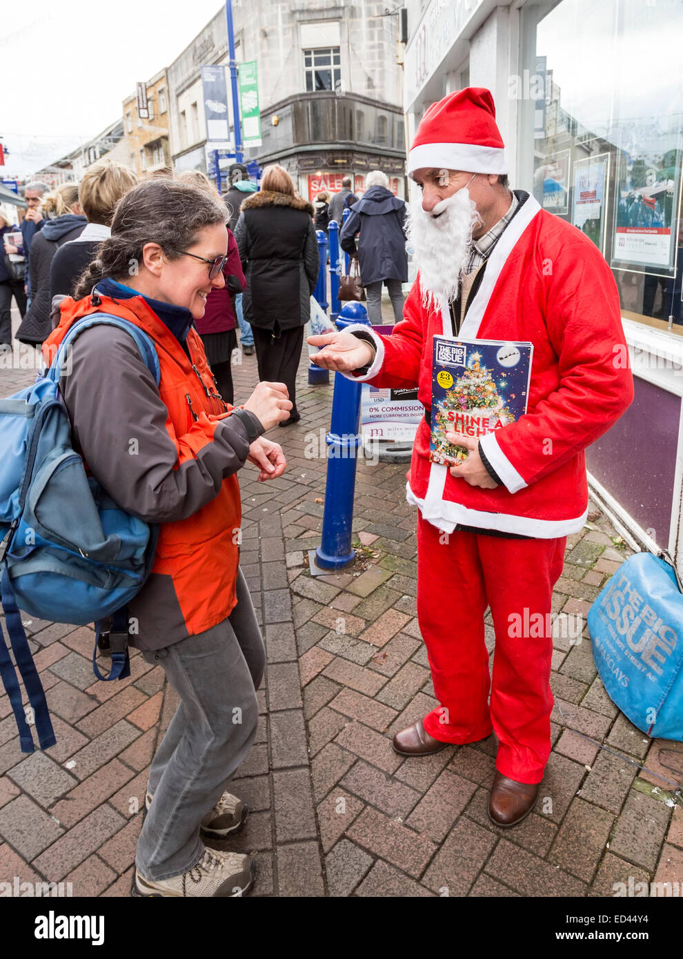 Big Issue seller on street at Christmas, Abergavenny, Wales, UK Stock Photo